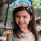 A little girl wearing a Great Pretenders Mermalicious Headband adorned with sequins and pearls.