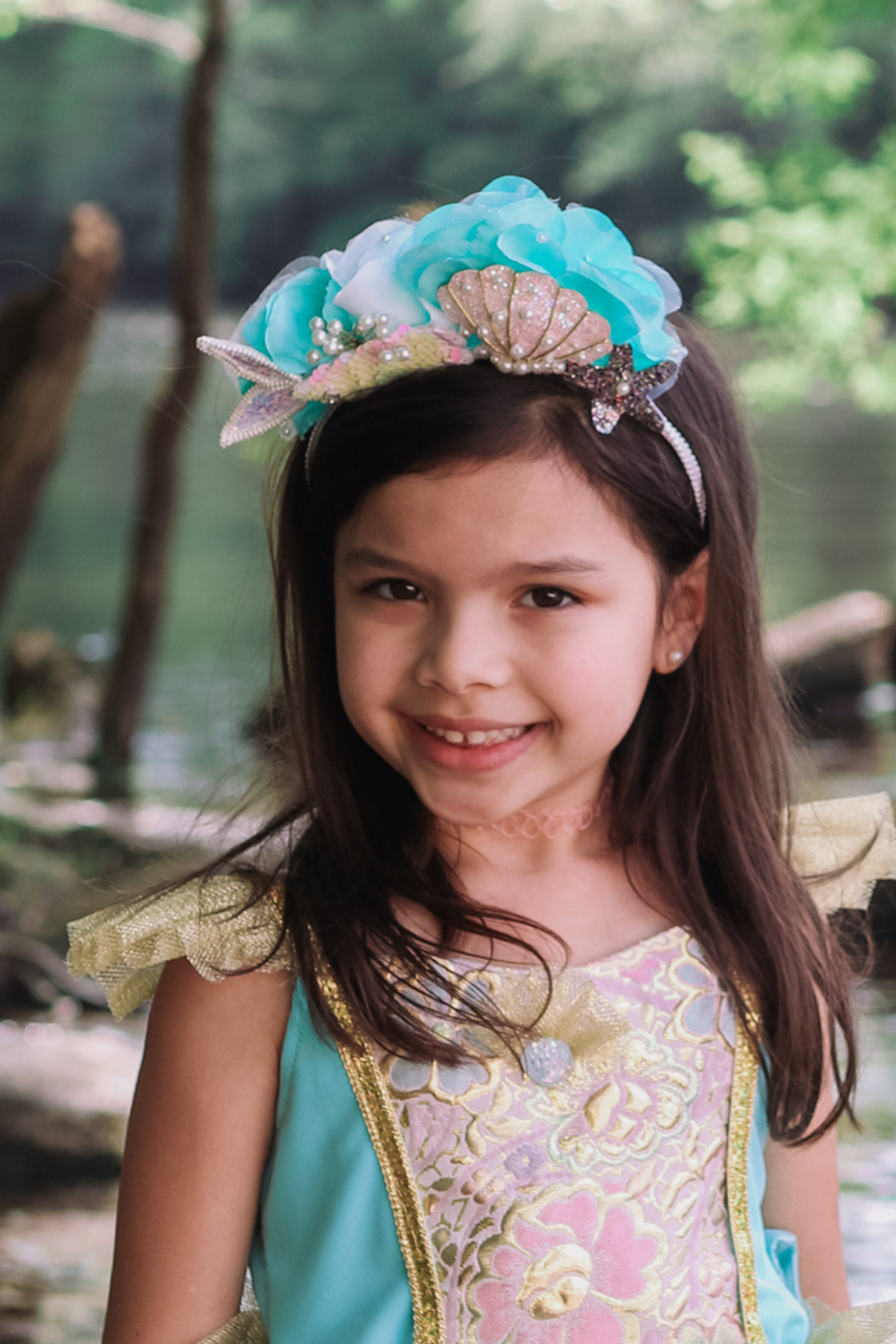 A little girl wearing a Great Pretenders Mermalicious Headband adorned with sequins and pearls.