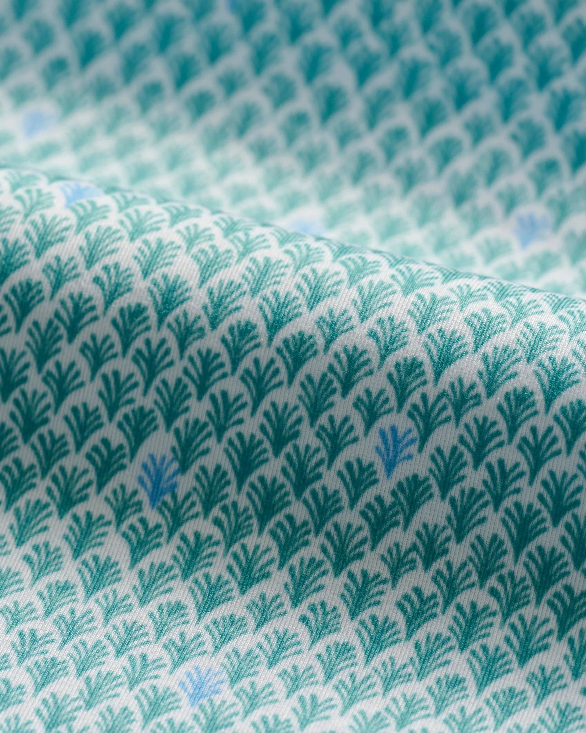 Close-up of the Johnnie-O Featherweight Performance Fernando Polo, showcasing its lightest weight jersey fabric with a blue and green floral pattern on white, offering UPF 50 sun protection.