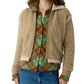 A person wears the Grizzly Frankie Jacket by Guest in Residence over a green and brown argyle sweater with blue jeans, shown from chest to hips.