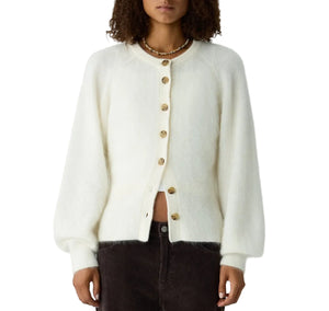 A person in a Grizzly Sculpted Cardigan by Guest in Residence and dark pants stands against a plain white background.
