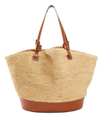 The Staud Squillo Raffia Tote by Staud is a striking straw bag with brown leather handles and trim, featuring a wide, structured base. It beautifully blends raffia and leather for a timeless accessory ideal for any outing.