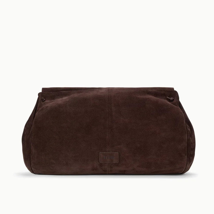 The Cy Oversized Bag by Staud, a large rectangular clutch crafted from brown suede as a bold statement accessory, is displayed against a plain white background.