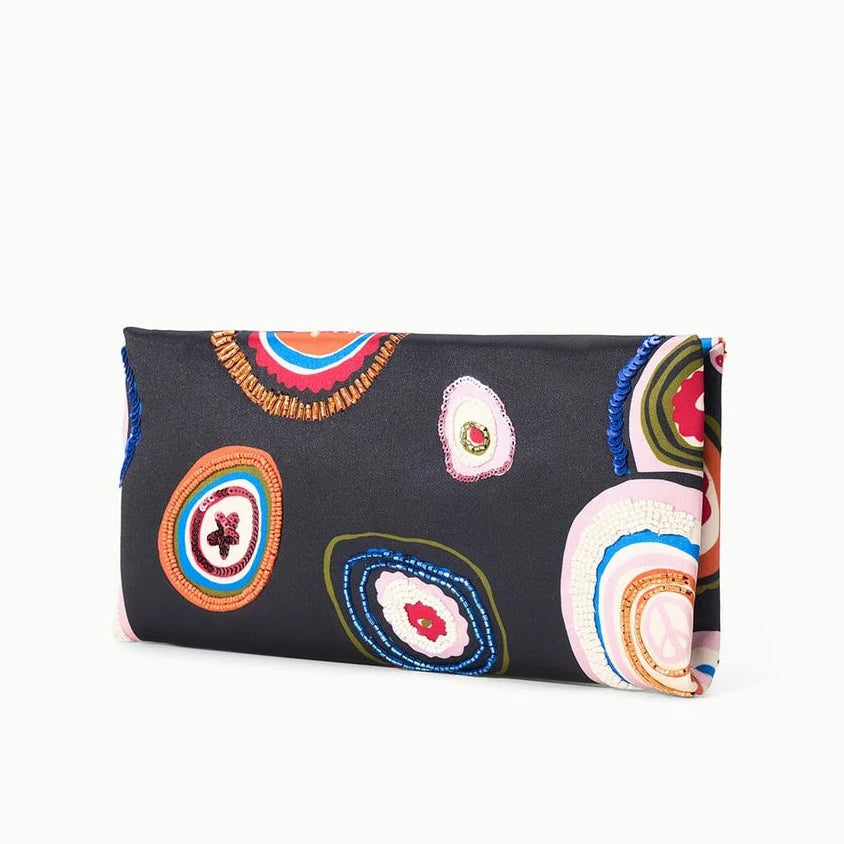 The Staud Muse Beaded Clutch features a rectangular silhouette with a black background adorned in vibrant, beaded concentric circles of various sizes and hues, making it the perfect compact accessory for special occasions.