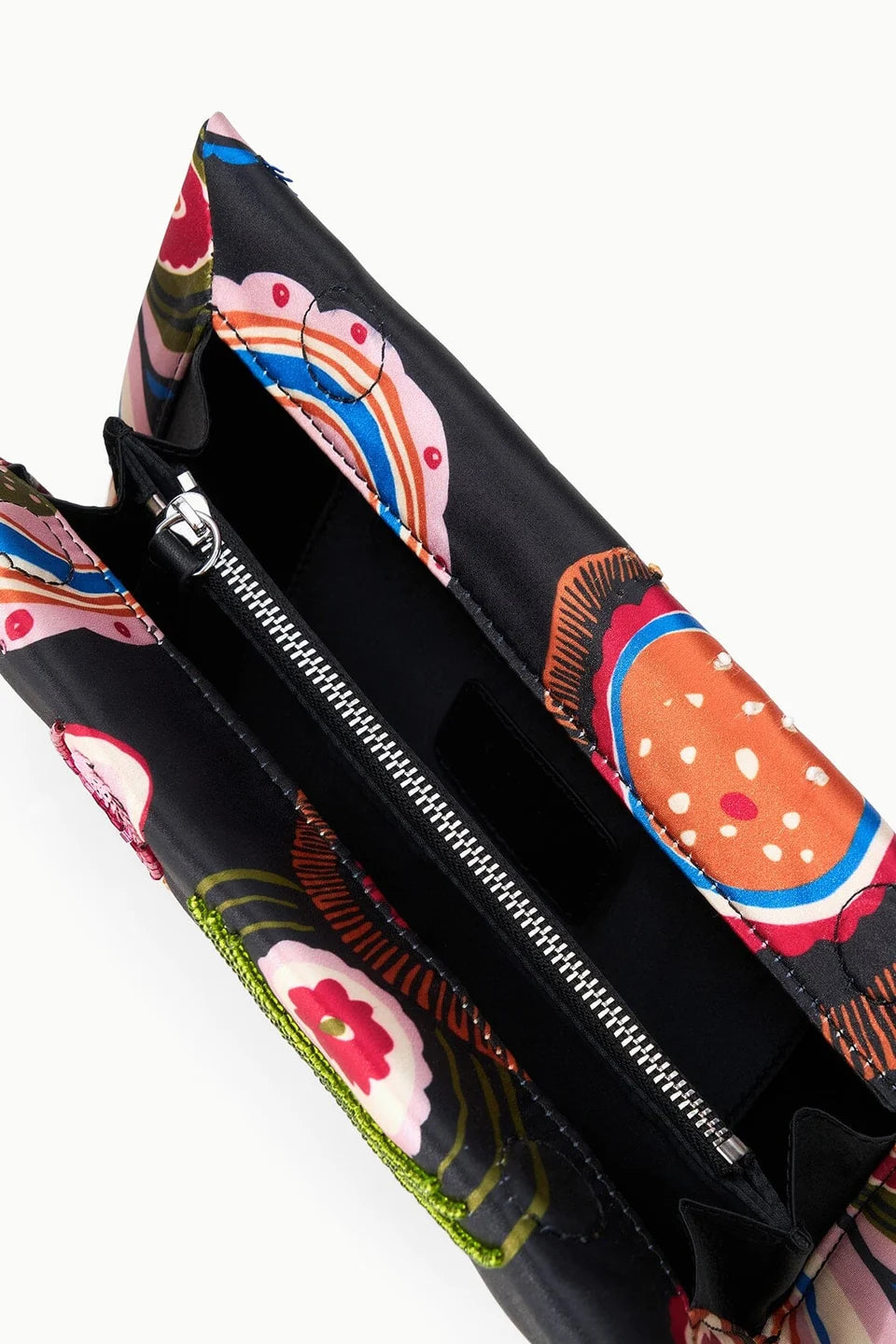 Close-up of the Staud Muse Beaded Clutch, an open black evening clutch adorned with a vibrant floral beaded pattern. It features a silver zipper pocket and black fabric lining inside, making this compact silhouette the perfect accessory for any special occasion.
