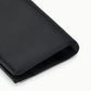 A close-up of a folded black satin pocket square on a white background, ideal as an evening accessory to complement occasion dresses or pair elegantly with the Staud Muse Clutch.