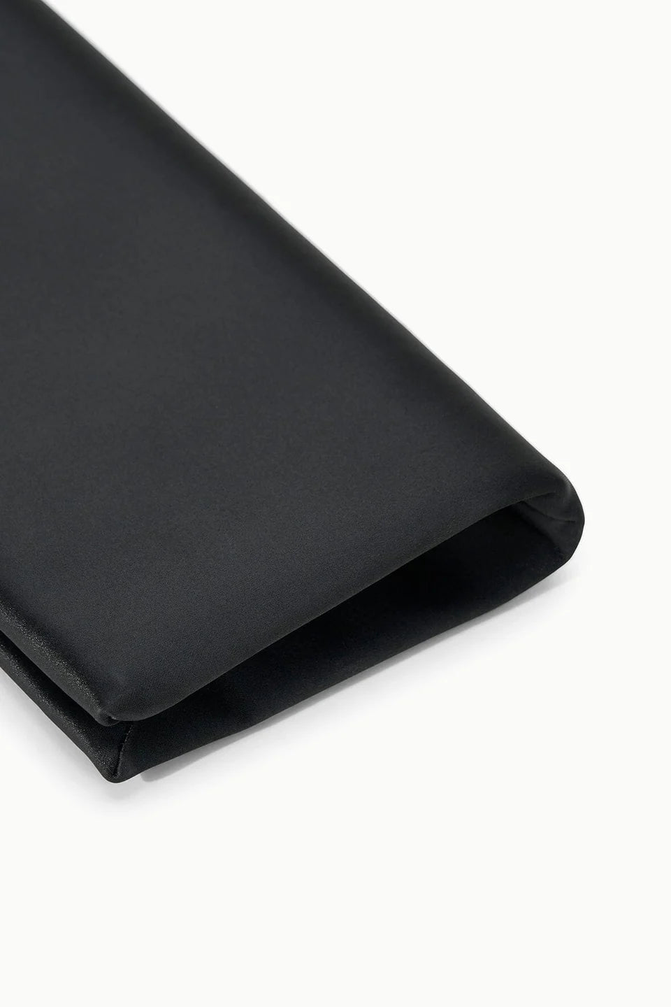 A close-up of a folded black satin pocket square on a white background, ideal as an evening accessory to complement occasion dresses or pair elegantly with the Staud Muse Clutch.
