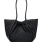 The Proenza Schouler Large Ruched Puffy Nylon Tote features a black gathered body, rigid looped handles, and a subtle gold-tone logo stamp, shown against a white backdrop.