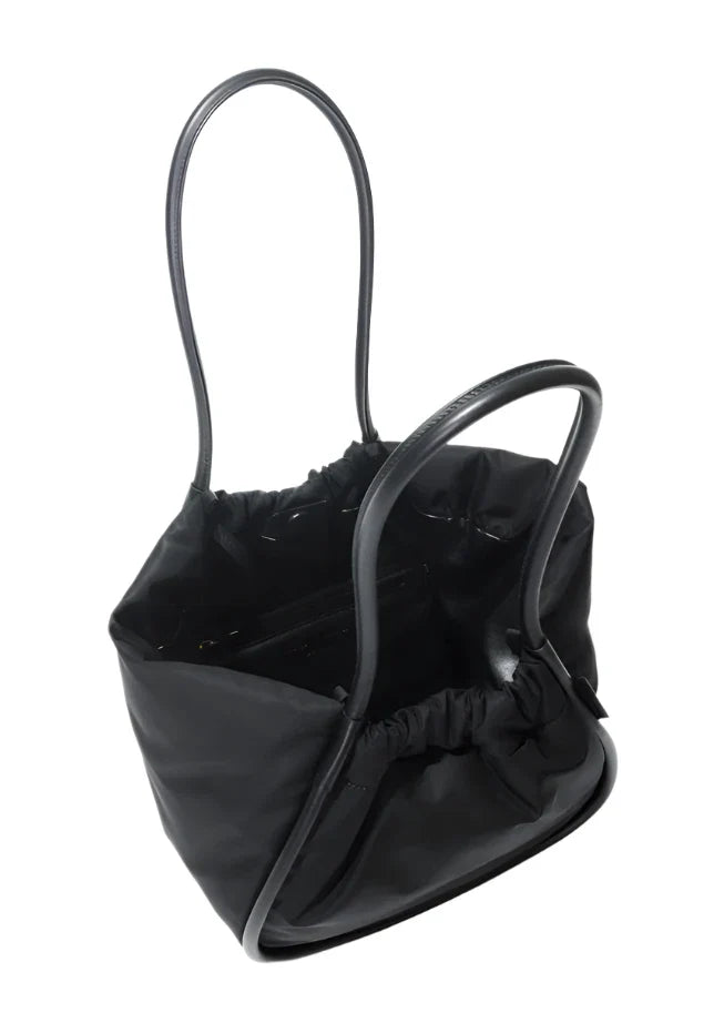 The Proenza Schouler Large Ruched Puffy Nylon Tote features a stylish drawstring opening, dual handles, and an elegant gold-tone logo accent.