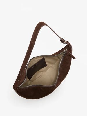 The Proenza Schouler Slide Suede Bag is a brown suede slide bag with a curved silhouette, zippered opening, beige interior lining, and an inner pocket, shown from an overhead angle.