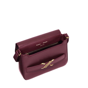 The Proenza Schouler Monogram Box Bag features a structured burgundy leather design with a gold clasp, crossbody silhouette, front pocket, and zippered main compartment.
