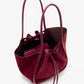 The Proenza Schouler Large Ruched Soft Suede Tote in burgundy features leather handles, a drawstring closure, matching wallet, and subtle gold-tone logo for an elegant finish.