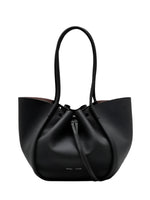 The Proenza Schouler Large Ruched Soft Pebbled Calf Tote is a black pebbled leather bag with two handles, a drawstring closure, and a detachable leather zip pouch.