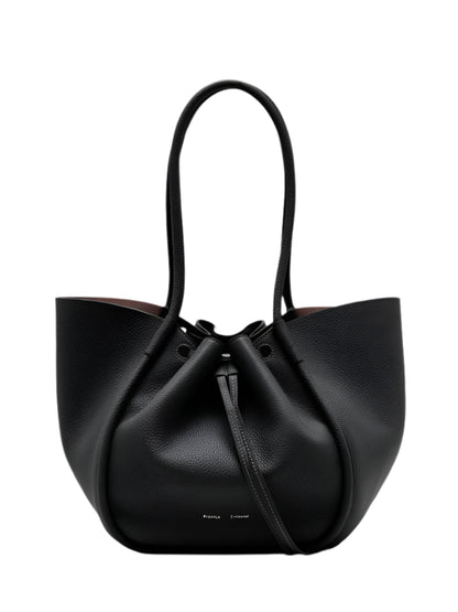 The Proenza Schouler Large Ruched Soft Pebbled Calf Tote is a black pebbled leather bag with two handles, a drawstring closure, and a detachable leather zip pouch.