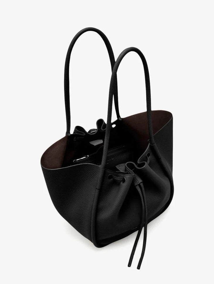 The Large Ruched Soft Pebbled Calf Tote by Proenza Schouler is a black bucket bag with two shoulder straps and a drawstring closure, featuring a roomy interior—an ideal match for your favorite leather zip pouch.