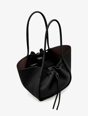 The Large Ruched Soft Pebbled Calf Tote by Proenza Schouler is a black bucket bag with two shoulder straps and a drawstring closure, featuring a roomy interior—an ideal match for your favorite leather zip pouch.