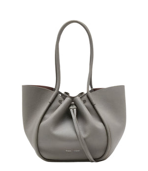 The Proenza Schouler Large Ruched Soft Pebbled Calf Tote in grey features a drawstring closure, two long handles, and comes with a matching leather zip pouch, all set against a plain white background.