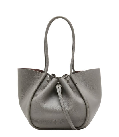 The Proenza Schouler Large Ruched Soft Pebbled Calf Tote in grey features a drawstring closure, two long handles, and comes with a matching leather zip pouch, all set against a plain white background.