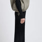 A person in a long black ribbed dress and black boots stands in profile, carrying the Proenza Schouler Large Ruched Soft Pebbled Calf Tote on their shoulder, with a leather zip pouch peeking out for added style.