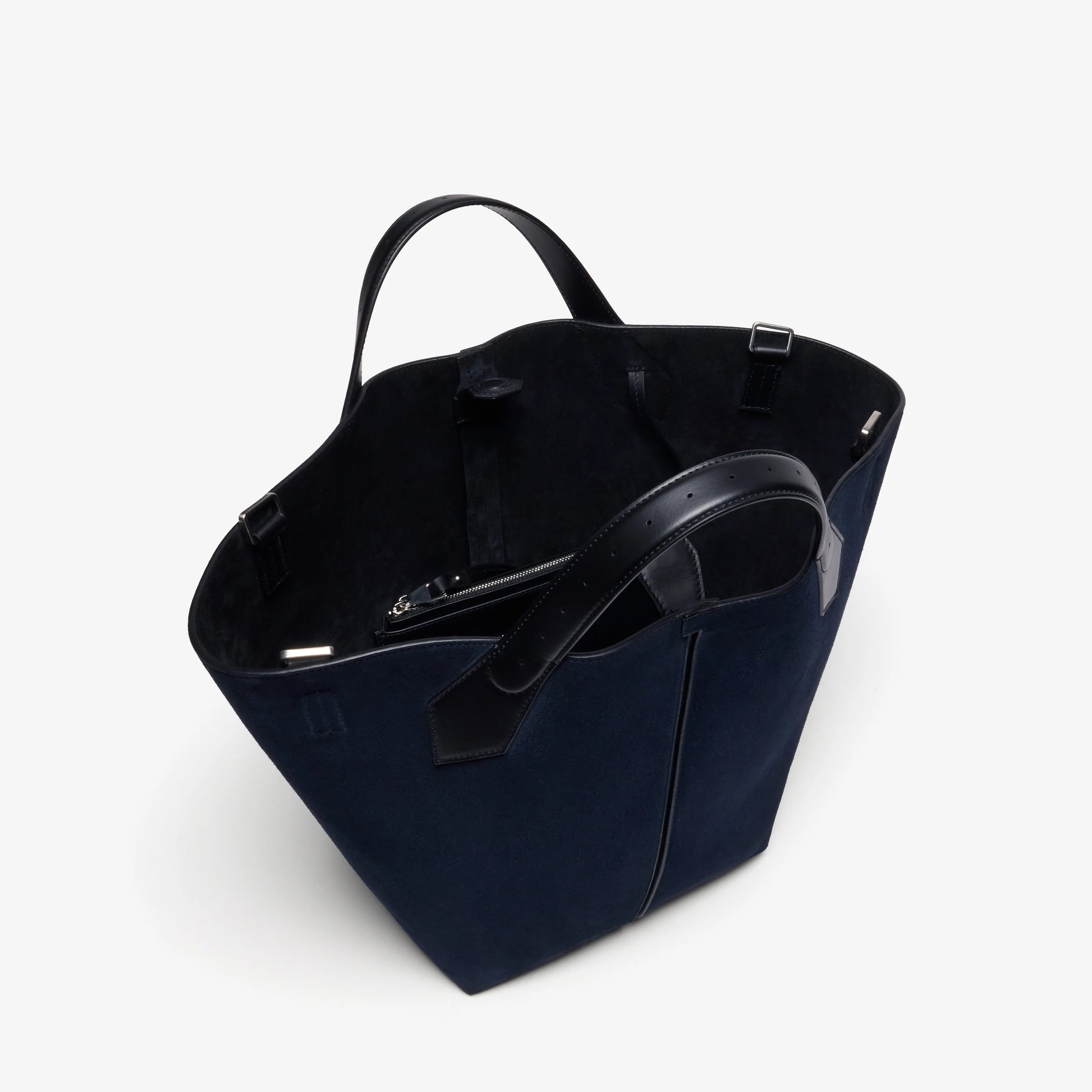 The Proenza Schouler Chelsea Large Soft Suede Tote is crafted in navy blue suede with black leather handles, showcasing an unstructured silhouette and a spacious open interior, displayed against a plain white background.