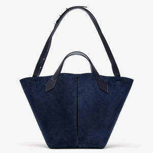 A navy blue Chelsea Large Soft Suede Tote by Proenza Schouler, featuring two handles and a wide, angular, unstructured silhouette, is displayed against a plain white background. This tote blends modern elegance with everyday versatility.