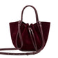 The Proenza Schouler Small Ruched Soft Suede Tote features soft burgundy suede, leather handles, a sculptural shape, long adjustable shoulder strap, and drawstring closure.