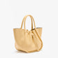 The Proenza Schouler Small Ruched Soft Pebbled Calf Tote in light yellow features double handles, a ruched open top, and a drawstring closure, shown against a plain white background.