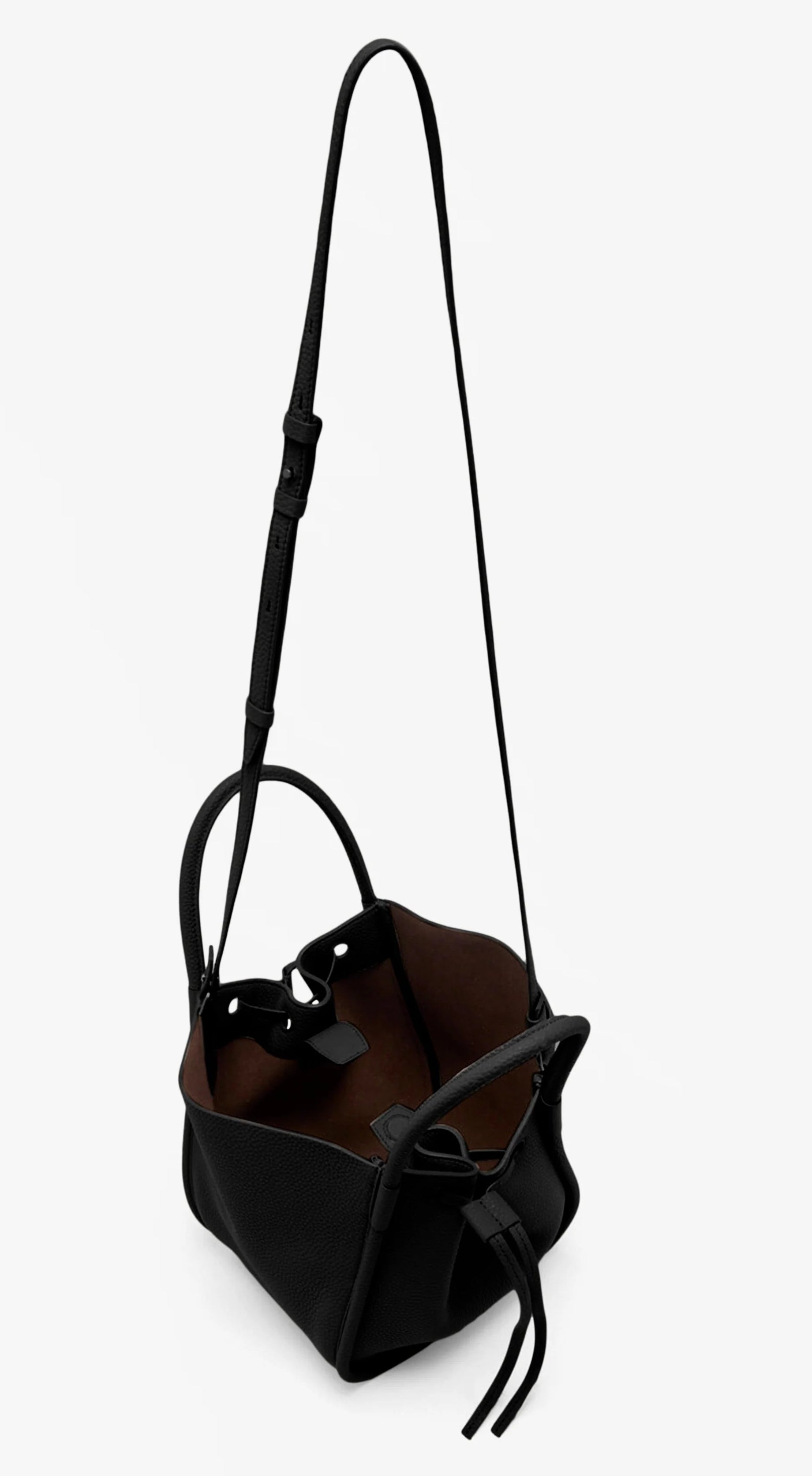 The Proenza Schouler Small Ruched Soft Pebbled Calf Tote is a black leather bucket bag with an adjustable shoulder strap, ruched open top, brown interior lining, and sculptural silhouette, shown against a white background.