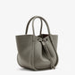 The Proenza Schouler Small Ruched Soft Pebbled Calf Tote is a textured gray leather bag with two handles and a ruched drawstring open top, shown against a white background.