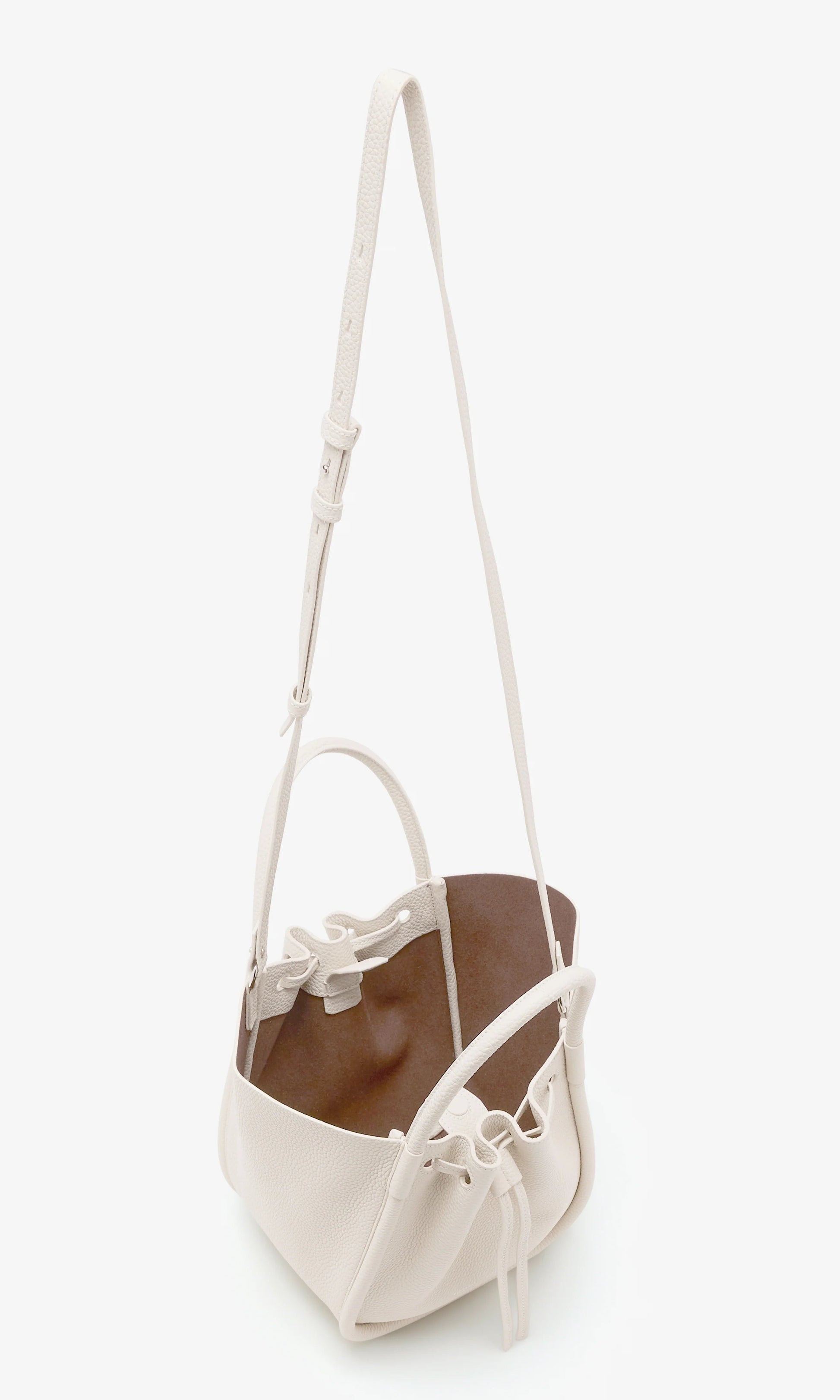 The Proenza Schouler Small Ruched Soft Pebbled Calf Tote is shown on a plain white background, featuring white leather, an adjustable shoulder strap, sculptural silhouette, drawstring closure, and brown interior.