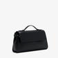 The Proenza Schouler Tate Clutch in black leather features a top handle, side buckle accents, a detachable crossbody strap, and a front flap closure, shown against a plain white background.