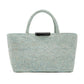 The East West Raffia Chelsea Tote by Proenza Schouler is a light blue woven bag featuring two sturdy handles and a black label at the top center, showcased against a plain white background.
