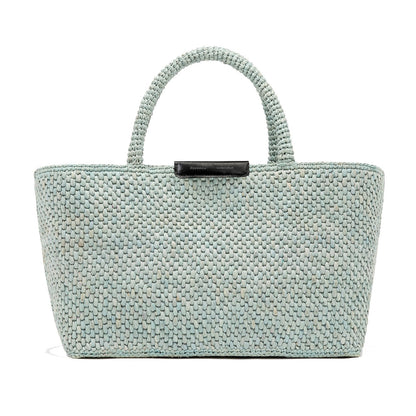 The East West Raffia Chelsea Tote by Proenza Schouler is a light blue woven bag featuring two sturdy handles and a black label at the top center, showcased against a plain white background.
