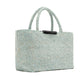 The East West Raffia Chelsea Tote by Proenza Schouler is a structured rectangular handbag in woven light blue, featuring two short handles and displayed at an angle against a white background.