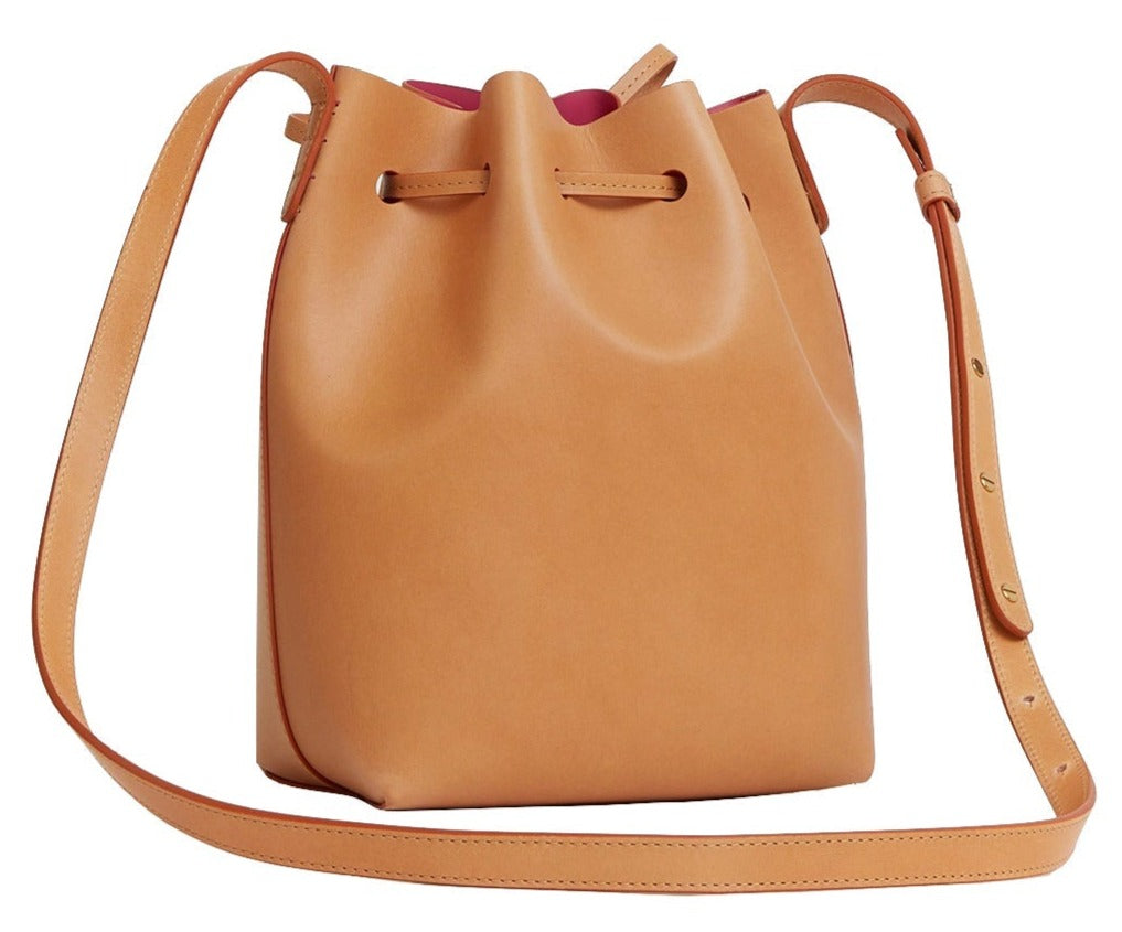 Mansur Gavriel Mini Bucket Bag by Mansur Gavriel is elegantly crafted from vegetable-tanned leather, showcasing a chic drawstring closure and an adjustable strap.