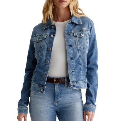 A person wearing an AG Robyn Denim Jacket in light blue AG Cloud Soft Denim™ and matching denim jeans is shown from mid-torso up. The individual sports a white top and a brown belt, completing the stylish look.