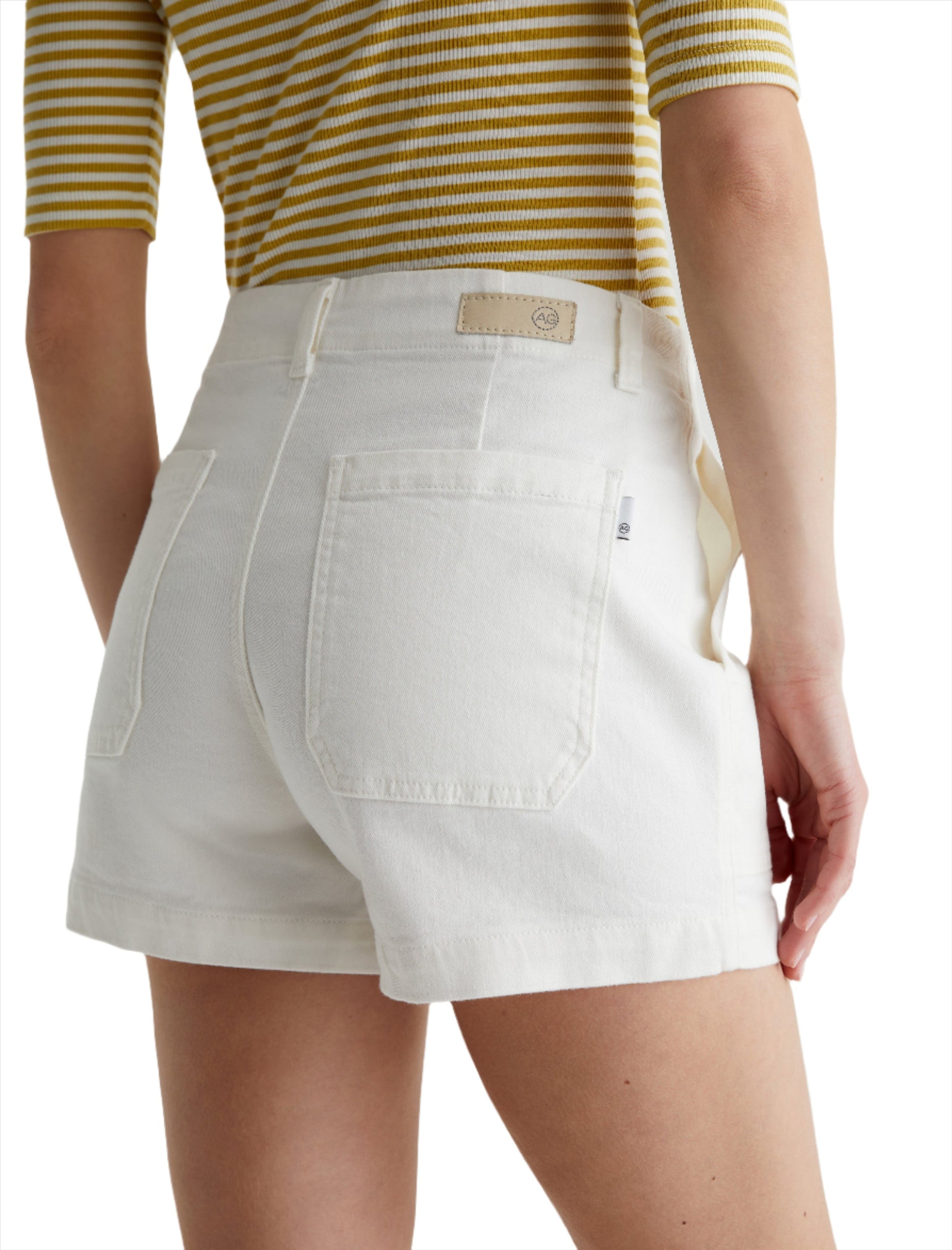 Rear view of a person wearing AG Jeans Analeigh Shorts with workwear-inspired back pockets. The person is also wearing a yellow and white striped top.