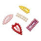 Adorn your hair with these five fashionable Super Smalls Chit Chat Pearl Snap Clips, each featuring pearl-like beads in an array of colors—yellow, white, pink, red, and purple. Perfect for stacking to achieve a chic look, these clips will effortlessly elevate any hairstyle.