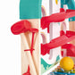 Close-up of the Hape Melody Mansion Ball Run, a house-shaped toy featuring a xylophone board, colorful ramps, a yellow ball, and two red mallets attached to the side with a red band.