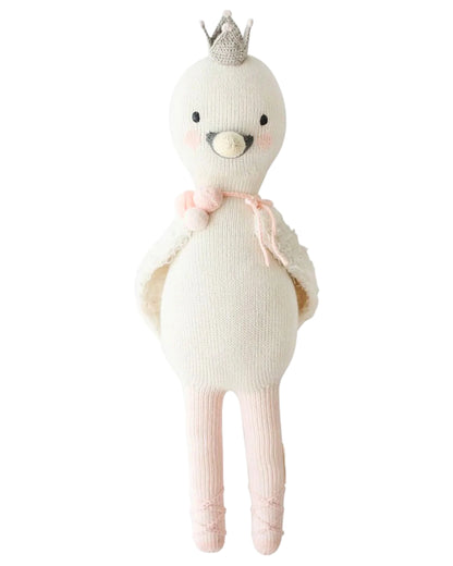 Harlow the Swan by Cuddle + Kind is a 20" knitted doll with a silver crown, pink blush, a pink tie, and ballet shoes—ready to dance with brave wings.