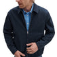 A man in a Rag & Bone Harrington Cotton Jacket over a blue striped button-up shirt stands against a white background, adjusting his jacket—a modern take on classic British sportswear.