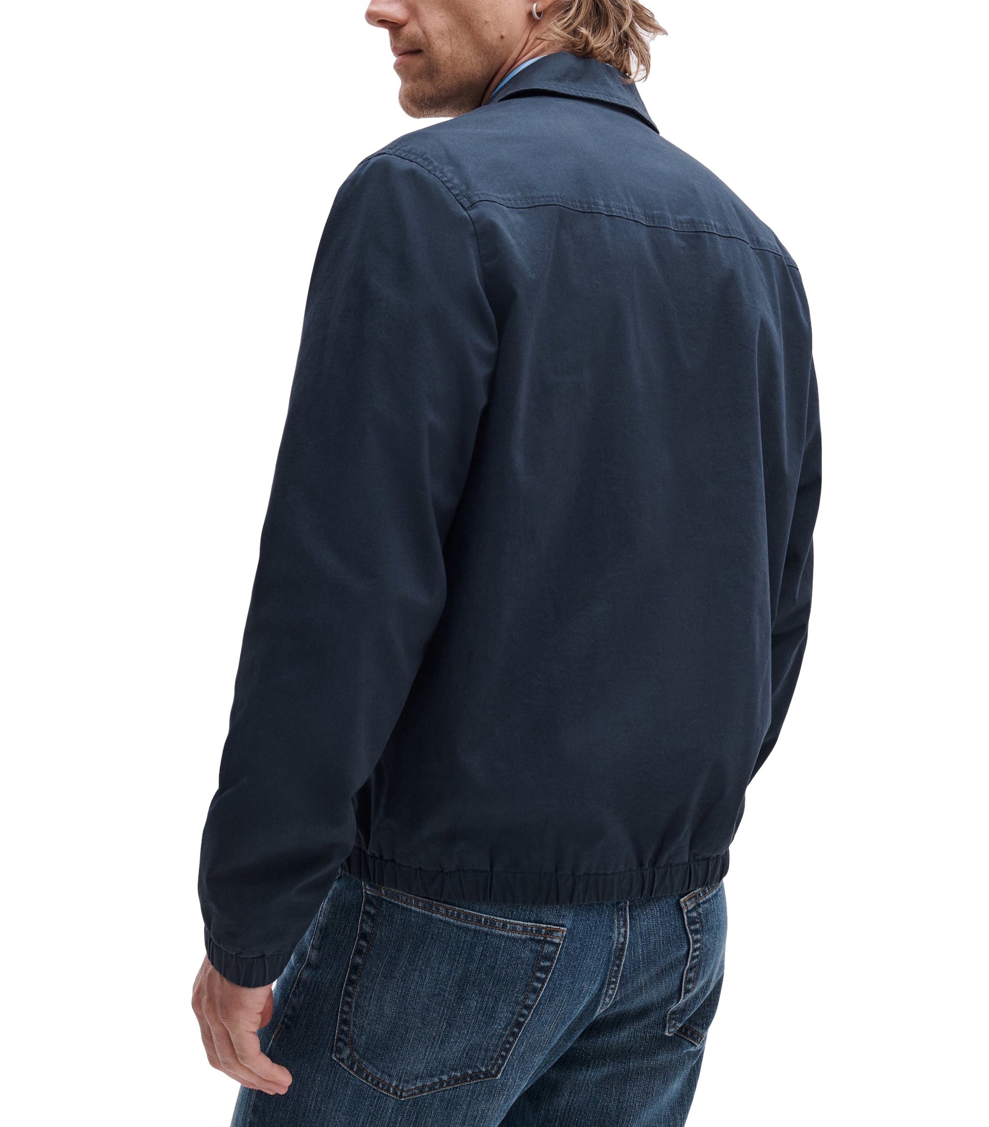 A man is shown from the back against a white background, wearing a Rag & Bone Harrington Cotton Jacket and blue jeans.