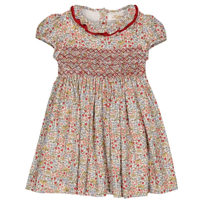 The Kidiwi Hars Smocked Dress by Kidiwi is a 100% cotton baby dress featuring a floral print, short sleeves, a red smocked bodice, and a ruffled collar.