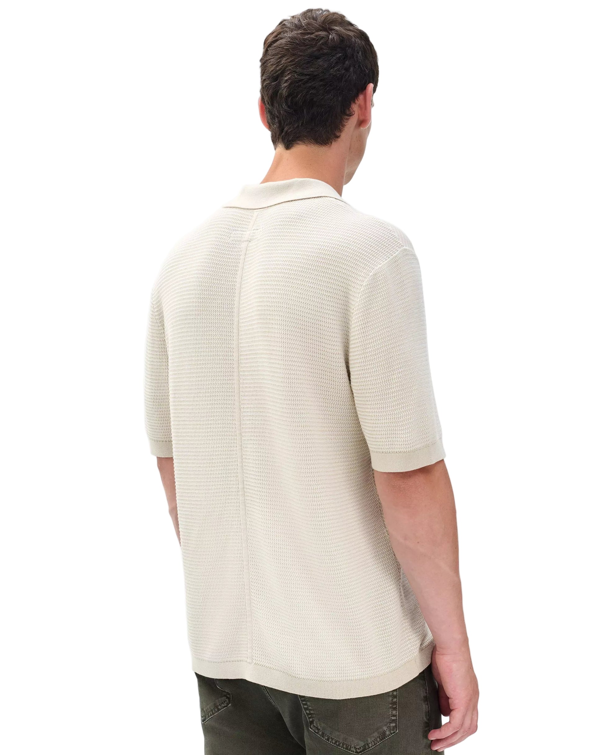 A person is shown from the back wearing the Rag & Bone Harvey Chevron Johnny Polo in light beige with short sleeves and no buttons, paired with olive green pants, against a white background.
