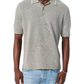 A man wears the Rag & Bone Harvey Knit Polo Shirt in light gray—a vintage-inspired, lightweight cotton blend short-sleeve top—paired with light blue jeans, standing against a white background.