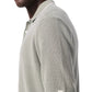 A man wears the Rag & Bone Harvey Knit Polo Shirt in light sage green, a short-sleeve cotton blend polo with a small logo tag on the sleeve cuff.