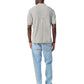 A man stands facing away, wearing the Rag & Bone Harvey Knit Polo Shirt in light gray, paired with light blue jeans and black shoes, against a white background.