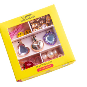 The Super Smalls Make It Heartfelt Mini Bead Kit comes in a yellow box with mini beads, heart-shaped charms, and pink string stored in divided compartments.