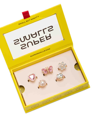 The Super Smalls Heartfelt Sparkle Ring Set comes in a yellow “Small But Mighty” box and includes five colorful kids’ rings with heart, butterfly, flower, pearl, and gemstone designs—perfect for dress-up fun.