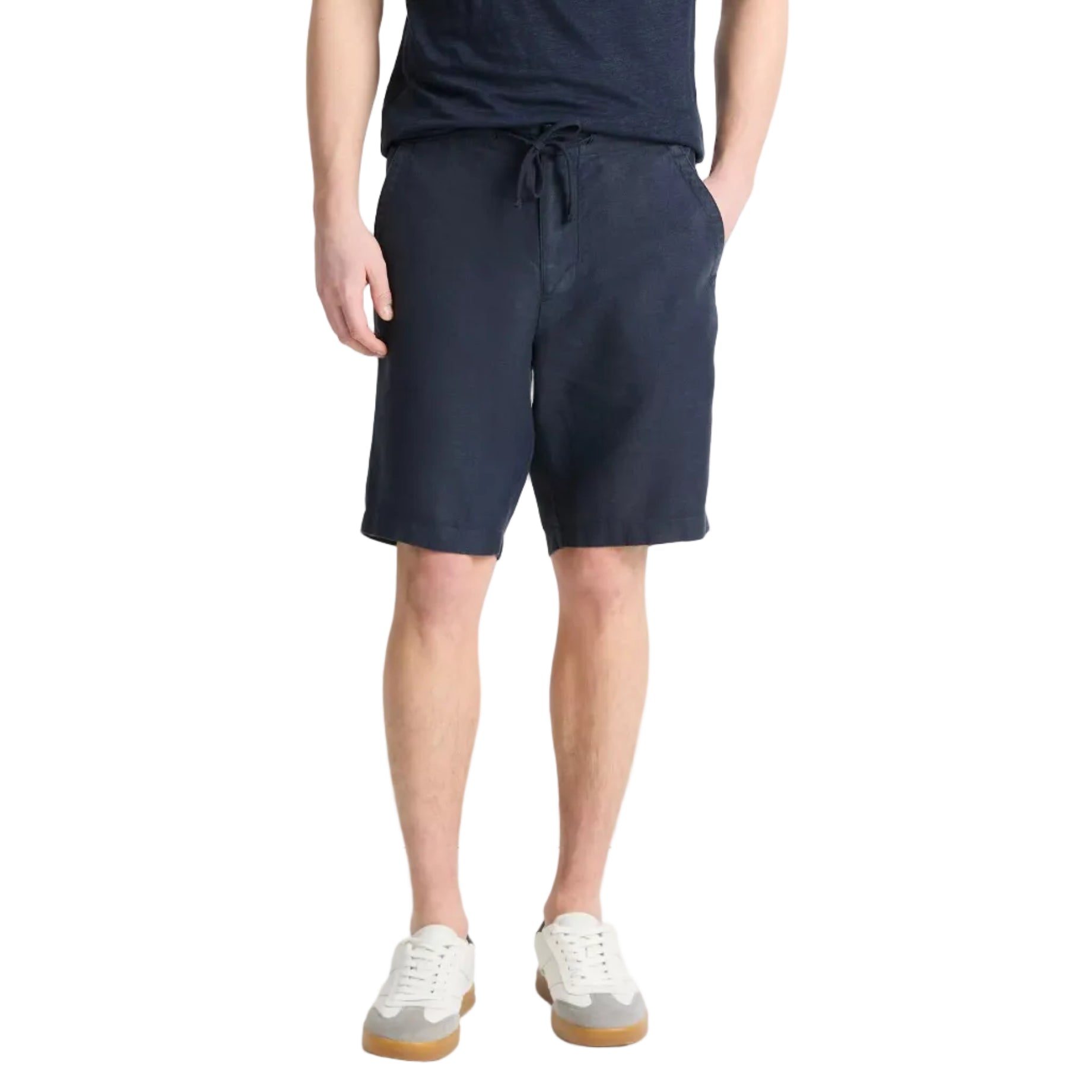 Someone stands against a plain background wearing a navy t-shirt, Vince Hemp Drawstring Short in navy, and white sneakers with gum soles.